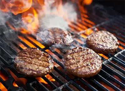 Burgers flaming on a hot grill
