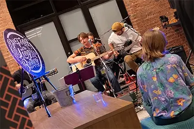 Live music with musicians playing acoustic guitar at Six Cord Apartments event