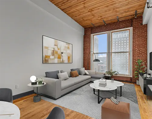 Loft-style living room with exposed brick, hardwood floors, and large windows with downtown city views