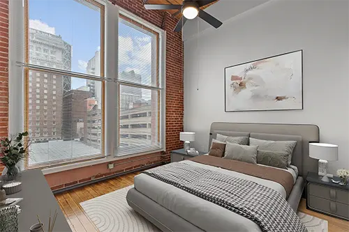 Bedroom in Six Cord Apartments with large windows showing downtown cityscape views